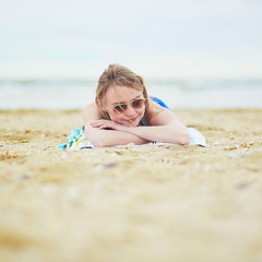 Young woman relaxing and sunbathing on sand beach