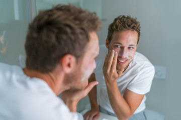 Man washing face with soap scrubbing exfoliation mask facial treatment looking in the mirror. Men...