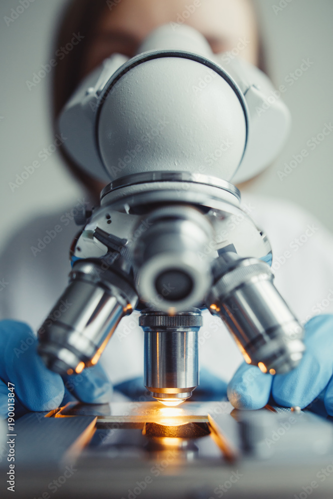 Wall mural close up of examining of test sample under the microscope in laboratory.