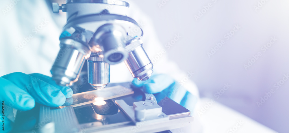 Wall mural close up of examining of test sample under the microscope in laboratory.