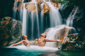 Wellness spa waterfall couple relaxing in nature waterfall with open arms in freedom. Relaxation in waterfall in tropical vacation. Holidays destination in paradise.