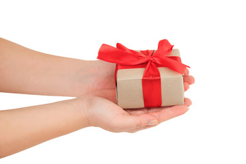 presentation of gift, female hands giving a gift wrapped with red ribbon on white background top view