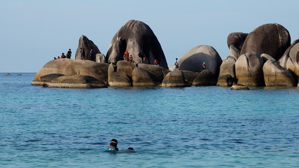 große runde Granitfelsen ragen aus dem Meer mit vielen Menschen als Größenvergleich 