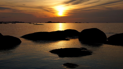 Fototapeta na wymiar malerischer Sonnenuntergang am Meer mit goldener Spiegelung im Wasser vor runden Felsen