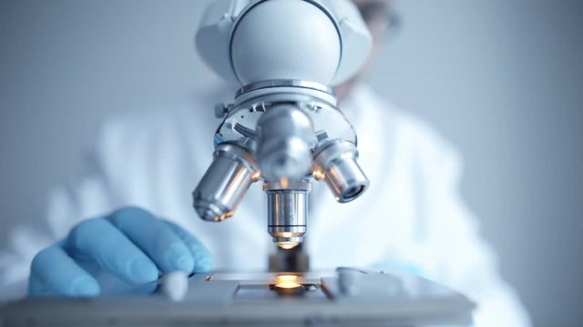Close up of examining of test sample under the microscope in laboratory.