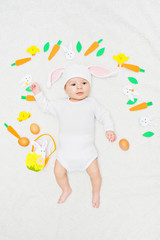 Baby in Easter bunny hat with garland, eggs and basket, flay lay