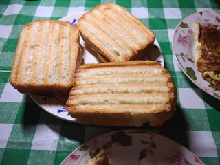Sandwiches and scrambled eggs on the kitchen table, home cooking, breakfast on a day off, American food, sandwich on the grill