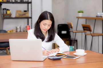 Fototapeta na wymiar Business asian woman writing on notebook on table with laptop, girl work at coffee shop, freelance business concept.