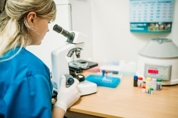 Specialist looks through a microscope in clinic