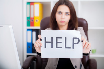 Stressed business woman imploring for help, holding a cardboard with the message 