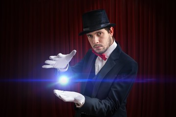 Young magician man is showing bright ball that levitates.