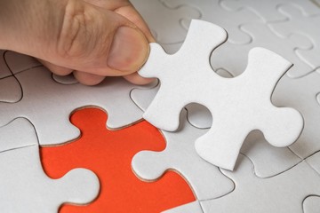 Obraz premium Hand of a man is connecting one last piece of white empty puzzle.