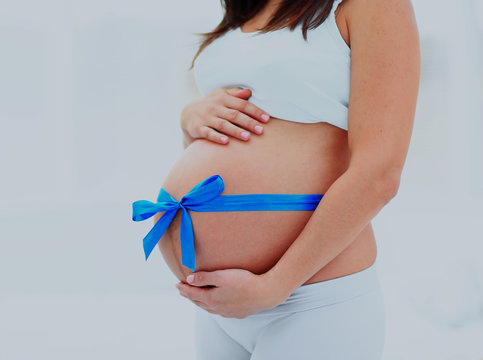 Woman Holds Her Baby Bump, Tied With A Blue Bow.