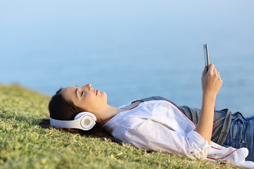 Woman relaxing listening to music on the grass