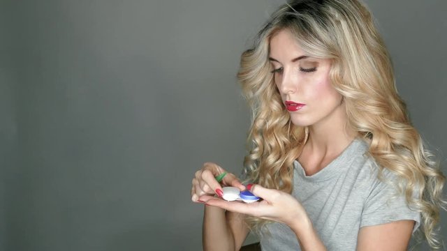 A transparent contact lens in the hands of a beautiful blonde who is preparing to insert it in her eyes.