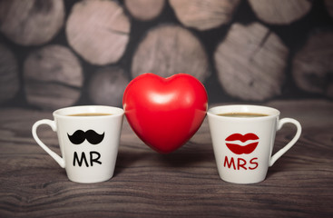 Two cups with a hot drink of lovers between them a red heart, mr and mrs, a man and a woman. Holiday, St. Valentine's Day, lovers' day, anniversary.