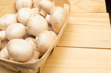 mushrooms champignons in a basket on a wooden background
