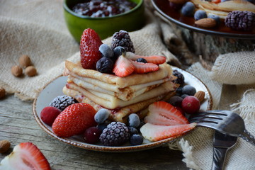 Thin pancakes with jam and berries