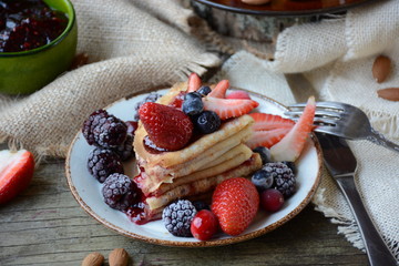 Thin pancakes with jam and berries