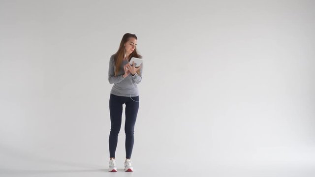 Smiling girl dancing while listening music on tablet