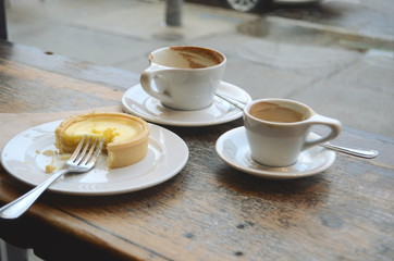 Empty coffee cups and a tart on a table at a city coffee shop