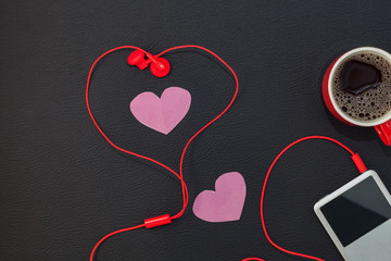 Red coffee cup with music player and red earphone on black leather background,Valentine's day concept.