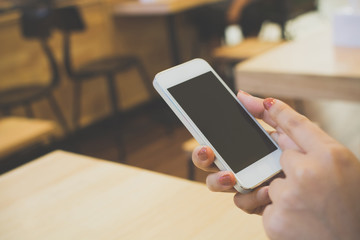 Close-up hand of female using smartphone on wooden table in restaurant, Template black screen device mobile phone