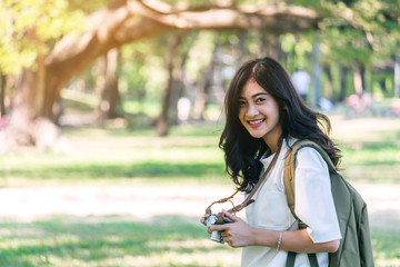 Asian woman taking picture with camera in park