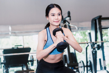 Fototapeta premium Sporty woman holding dumbbells with towel in the gym