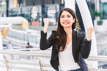 Successful businesswoman celebrating with arms up at office