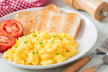 Scrambled egg served with toast and tomato .