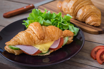 Croissant with ham, cheese and vegetable on plate