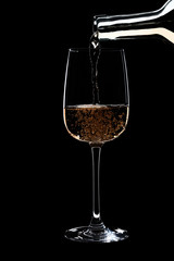 A glass of white wine is pouring wine from bottle of white .