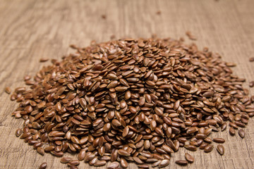 Brown Flax seed. Pile of grains on the wooden table. Selective focus.