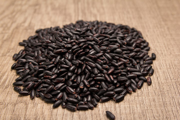 Black Rice seed. Pile of grains on the wooden table. Selective focus.