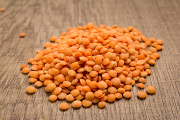 Turkish Red Lentil legume. Pile of grains on the wooden table. Selective focus.