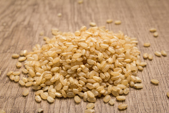 Whole Short Grain Rice Seed. Pile of grains on the wooden table. Selective focus.