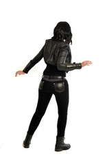 full length portrait of black haired girl wearing leather outfit. standing pose  view from behind, on a white background