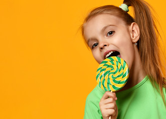 Happy young little child girl kid bite sweet lollypop candy