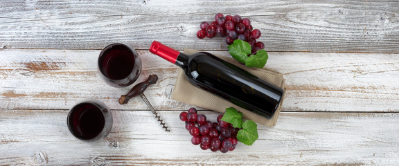 Red wine ready to drink with full bottle and grapes on white weathered wooden boards