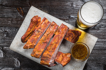 Snack to beer smoked pork ribs with a sauce of grainy mustard on the Board for filing is covered with a sheet of parchment. The view from the top. Copy-space.