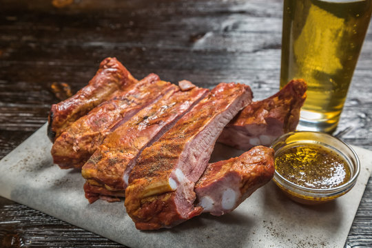 Snack to beer smoked pork ribs with a sauce of grainy mustard on the Board for filing is covered with a sheet of parchment. 