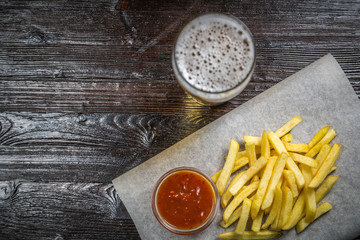 Beer snack of fries fries with gravy on the Board for filing is covered with a sheet of parchment. The view from the top. Copy-space.