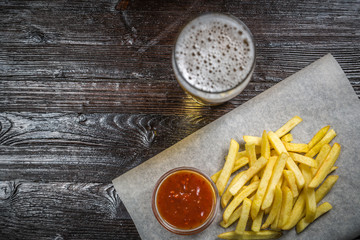 Beer snack of fries fries with gravy on the Board for filing is covered with a sheet of parchment....