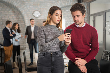 Young businessman and businesswoman posing in office