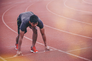 Man runner starting in the track. Fit male fitness runner jogging in stadium