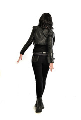 Fototapeta premium full length portrait of black haired girl wearing leather outfit. standing pose view from behind, on a white background