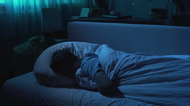 Cute school boy sleeping in comfortable bed at night, healthy sleep and relax