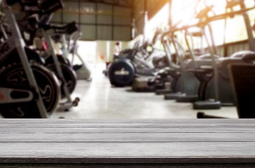 Wooden table on blurred background of fitness gym interior of modern club with equipment for your...