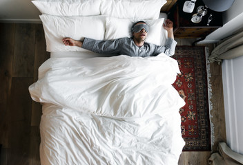 Man on bed sleeping with an eye cover